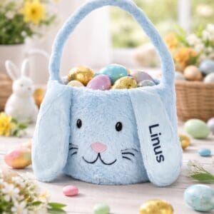 Personalisierter Osterkorb aus blauem Plüsch mit Hasenmotiv, gefüllt mit bunten Ostereiern, auf österlich dekoriertem Tisch